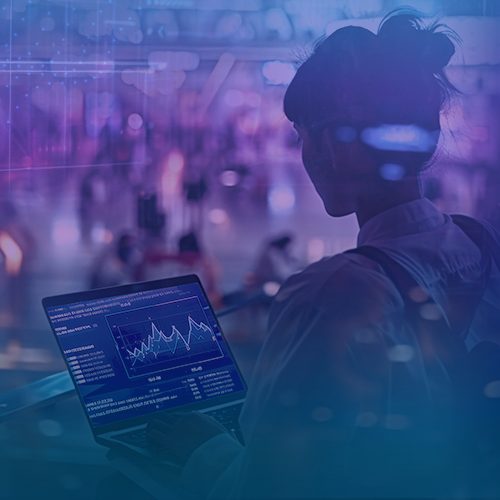 Uma mulher de costas trabalhando em um computador que mostra gráficos, como painéis de BI.