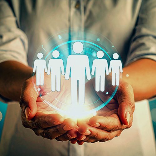 A imagem mostra as mãos de uma mulher segurando alguns bonecos ilustrativos que representam pessoas que serão desenvolvidas para futuras lideranças.