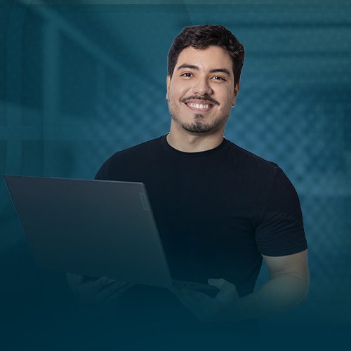 Um homem branco veste blusa preta e segura um notebook de cor cinza nas mãos. Na imagem ele sorri